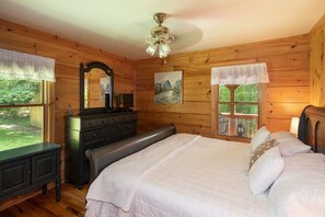A wooden cabin bedroom with a bed, dresser, and a large mirror.