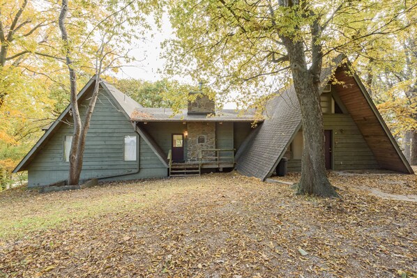 A cabin with a stone fireplace, wooden exterior, and a steeply pitched roof. - Charming, Private and Fully Furnished Lake Home on Grand Lake (Vinita)