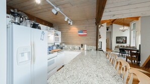 A kitchen with a granite countertop, wooden ceiling beams, and a flag on the wall.