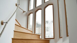 A wooden staircase with a rope handrail, leading to a room with large arched windows. - 3 bedroom accommodation in Ramsgate (Ramsgate)