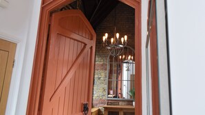 A red wooden door with a 'WELCOME' sign, a chandelier, and a brick wall. - 3 bedroom accommodation in Ramsgate (Ramsgate)