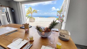 A dining table set with plates, cutlery, and a bowl of fruit. - Villa La Guapa sea view private pool 5 min from the beach (La Savane)