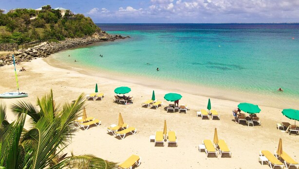 A beach with clear turquoise water, sandy shore, and several sun loungers with umbrellas. - Villa La Guapa sea view private pool 5 min from the beach (La Savane)