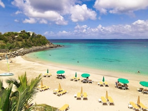 A beach with clear turquoise water, sandy shore, and several sun loungers with umbrellas. - Villa La Guapa sea view private pool 5 min from the beach (La Savane)