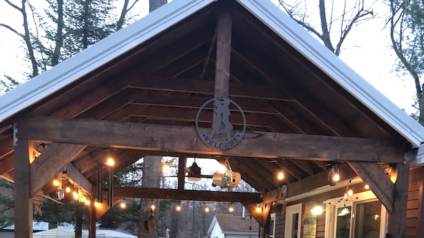 Un espace cuisine extérieur abrité, doté d’un plan de travail en pierre, de tabourets en bois et de guirlandes lumineuses.