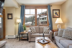 Un salon confortable avec un canapé, une table basse et une vue sur une station de ski.