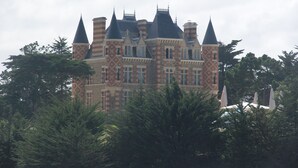 A large, historic building with multiple towers and turrets, surrounded by dense foliage. - Top-of-the-range mobile home (Dinard)