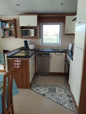 A compact kitchen with a microwave, toaster, sink, and dishwasher.
