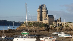 A castle with a moat, surrounded by boats on a rocky shore. - Top-of-the-range mobile home (Dinard)