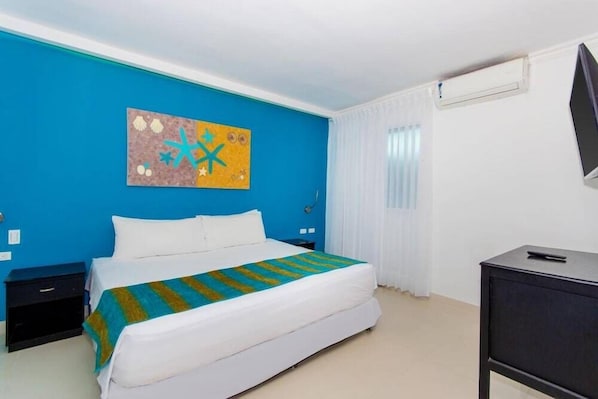 A hotel room with a bed, a desk, a TV, and a painting on the wall. - Bocagrande Cartagena De Indias (Cartagena)