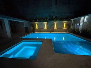 A swimming pool with illuminated edges and a tiled deck area.