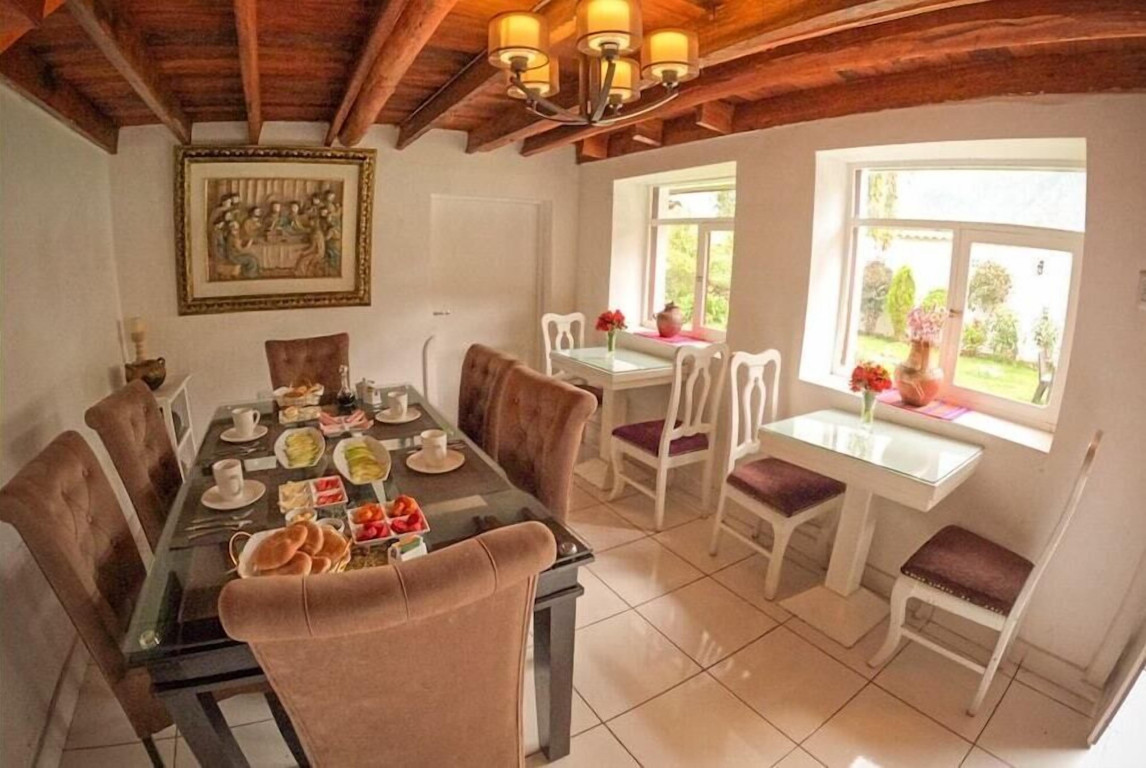 A dining area with a glass table, white chairs, and a wooden ceiling.