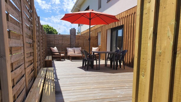 A wooden deck with outdoor furniture, including a bench, chairs, and a table. - Self-contained apartment, patio with terrace and bicycle paths (La Teste-de-Buch)