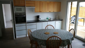 A compact kitchen with a dining area, featuring a microwave, coffee maker, and a sink. - Self-contained apartment, patio with terrace and bicycle paths (La Teste-de-Buch)