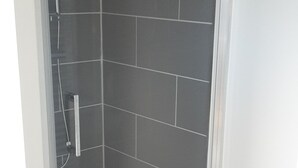 A walk-in shower with a glass door, tiled walls, and a small mat at the entrance. - Self-contained apartment, patio with terrace and bicycle paths (La Teste-de-Buch)