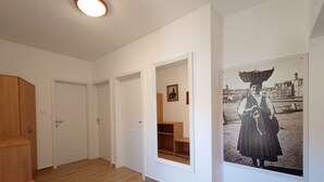 Un corridoio con pavimento in legno, pareti bianche e una grande fotografia incorniciata sulla destra.
