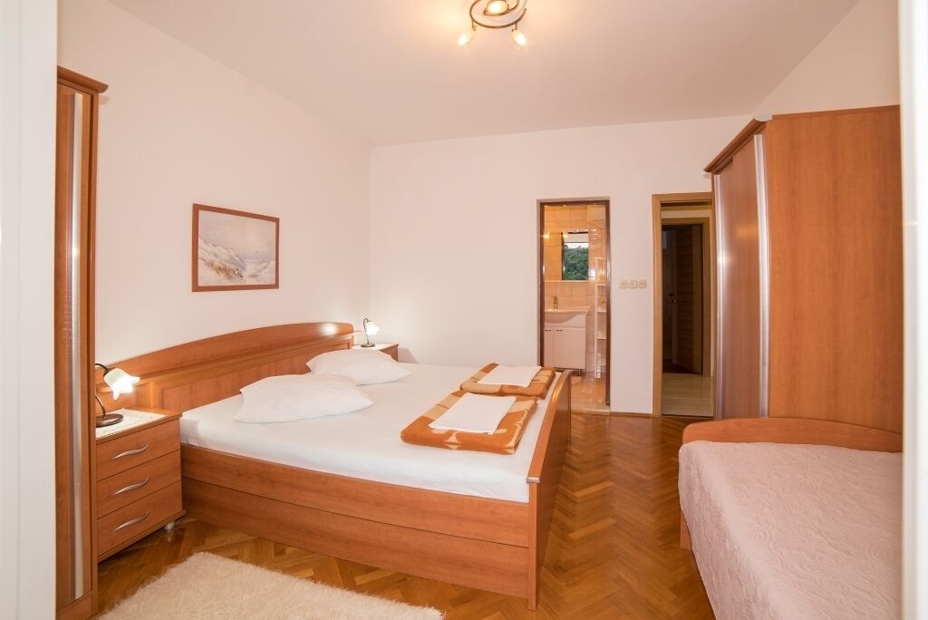 A bedroom with a wooden bed, a nightstand, a dresser, and a framed picture on the wall.