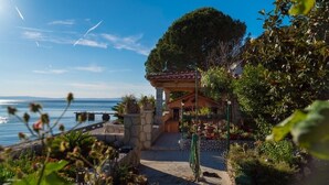Ein Küstenanwesen mit einem gepflasterten Weg, der zu einem Pavillon führt, mit Blick auf das Meer.