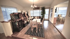 A dining area with a wooden table and chairs, a black and pink arcade machine, and a potted plant. - SECRET LAKE HIDEAWAY (Eagle Rock)