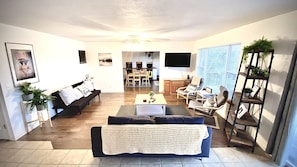 A living room with a sofa, armchairs, a coffee table, and a TV. There is a kitchen in the background. - SECRET LAKE HIDEAWAY (Eagle Rock)
