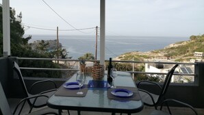 A balcony with a table set for two, overlooking a coastal view. - George place two-storey holiday home offers panoramic sea and mountain views. (Λυγαριά)