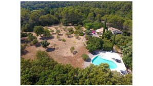 Vista aérea de una propiedad con piscina, rodeada de árboles y algunos edificios.