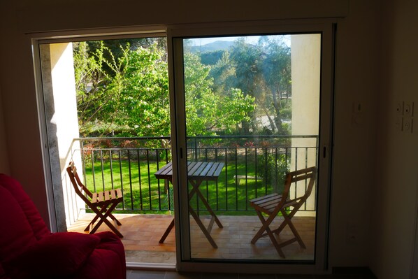 A room with a sliding glass door leading to an outdoor patio with a wooden table and two wooden chairs.