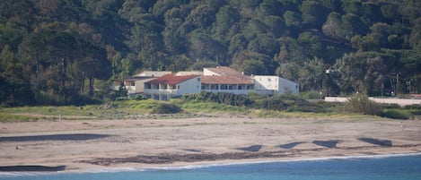 A coastal property with a large house surrounded by lush greenery and a beach.