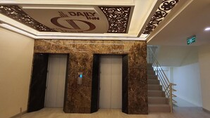 A hotel lobby with a marble column, a reception desk, and a staircase.