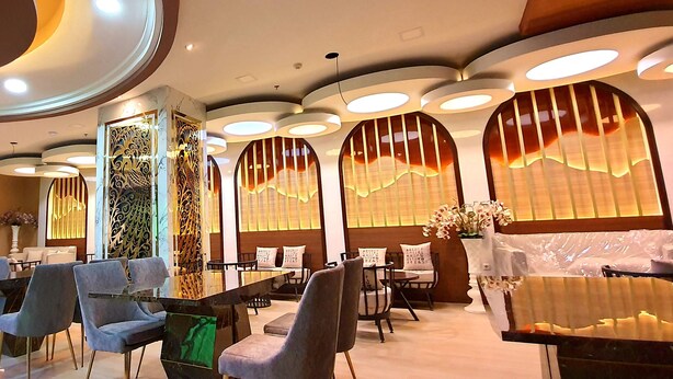 A modern restaurant with round tables, cushioned chairs, and decorative lighting.
