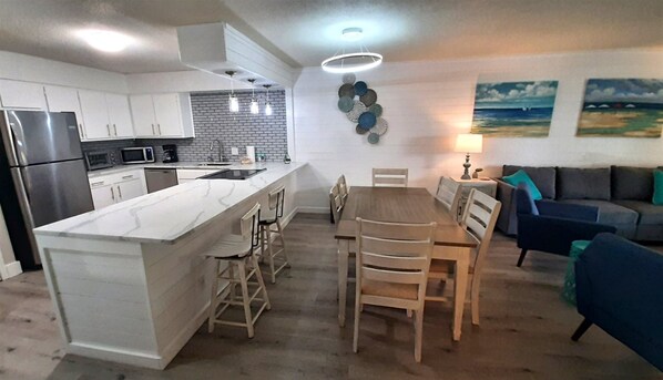 A modern kitchen with a central island, dining table, and chairs.