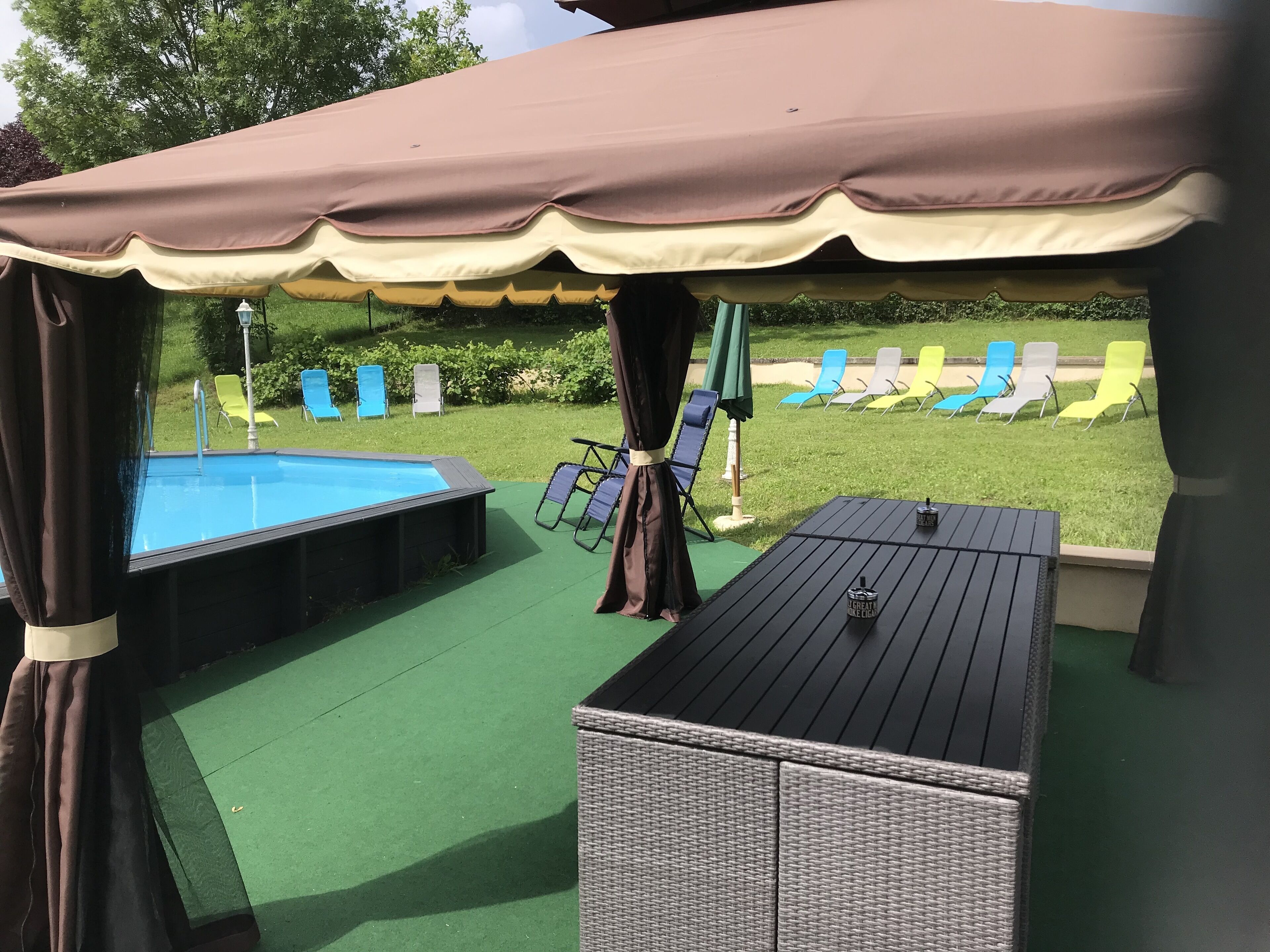 A covered outdoor area with a pool, lounge chairs, and a table.