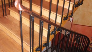 Een houten trap met zwarte metalen leuningen en een houten handrail.