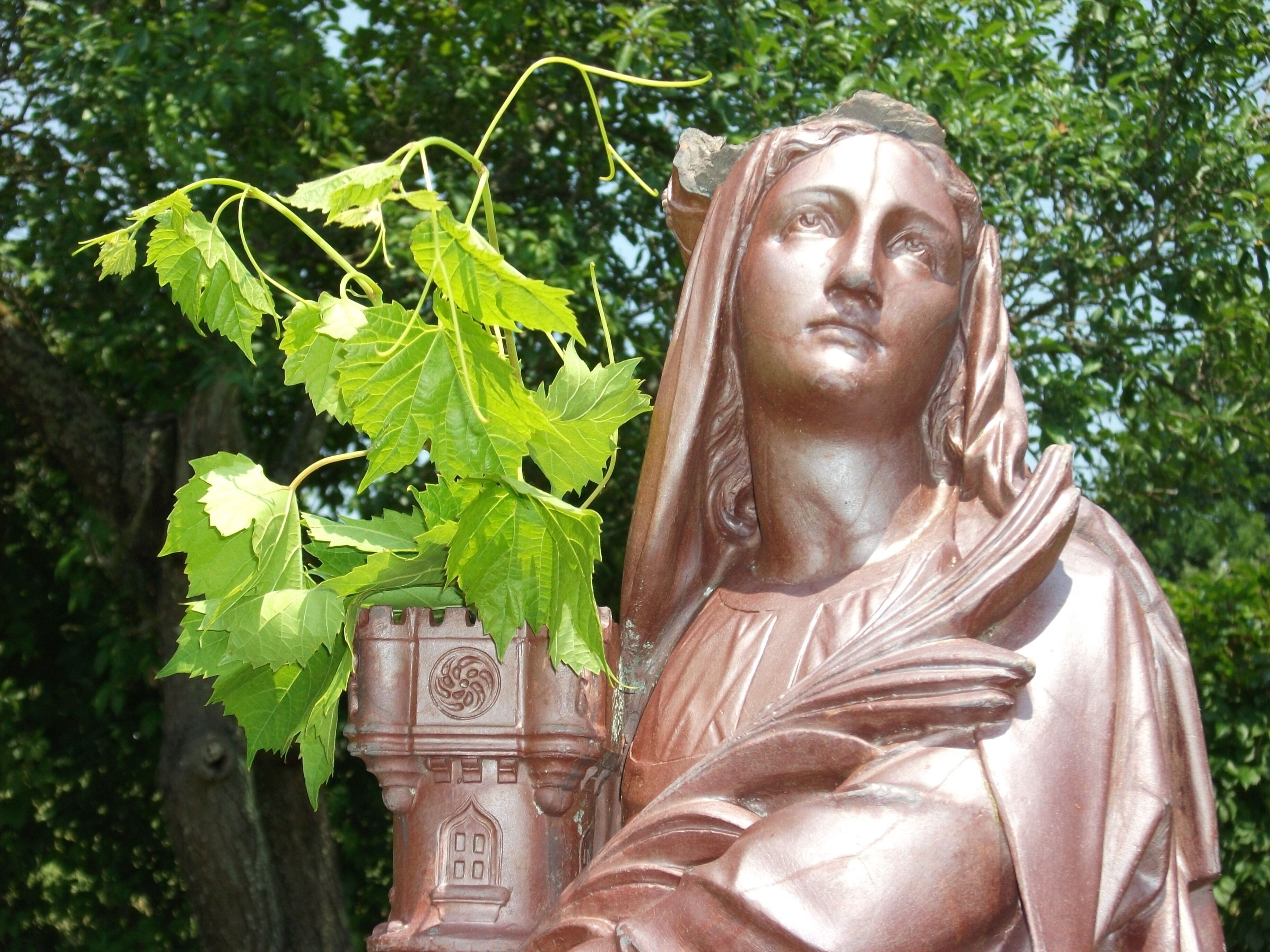 En statue i draperet klædning med en plante.