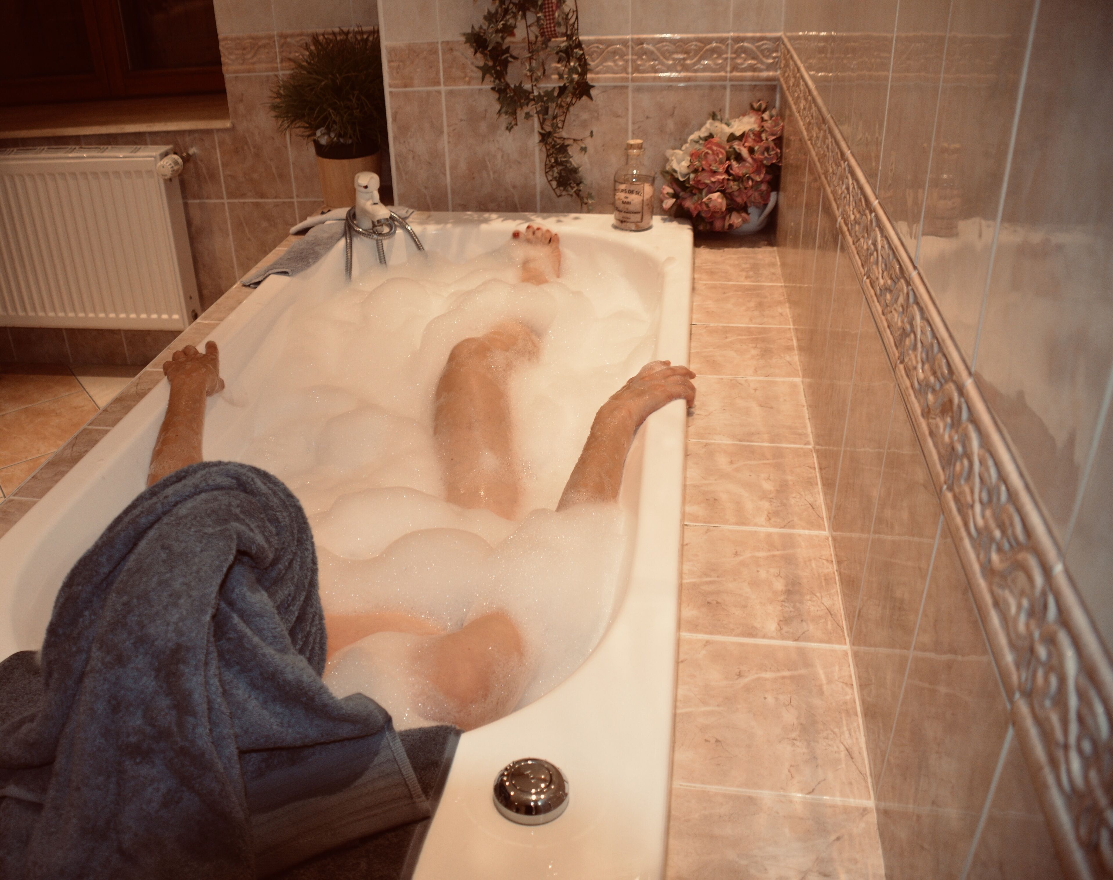 A person relaxing in a bathtub with a towel.