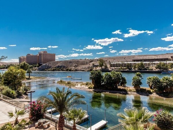 Vista del río con un puente, palmeras y un edificio al fondo.