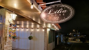 Un bâtiment sur lequel on peut lire l’inscription « Lilia House 92 », agrémenté d’une plante suspendue servant de décoration.
