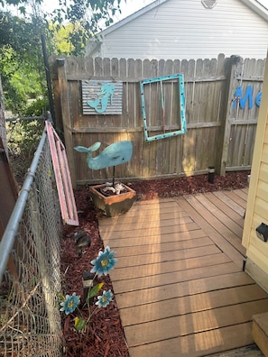 Eine Holzterrasse mit einem Metallzaun, einem Blumentopf und einem Blumenbeet.