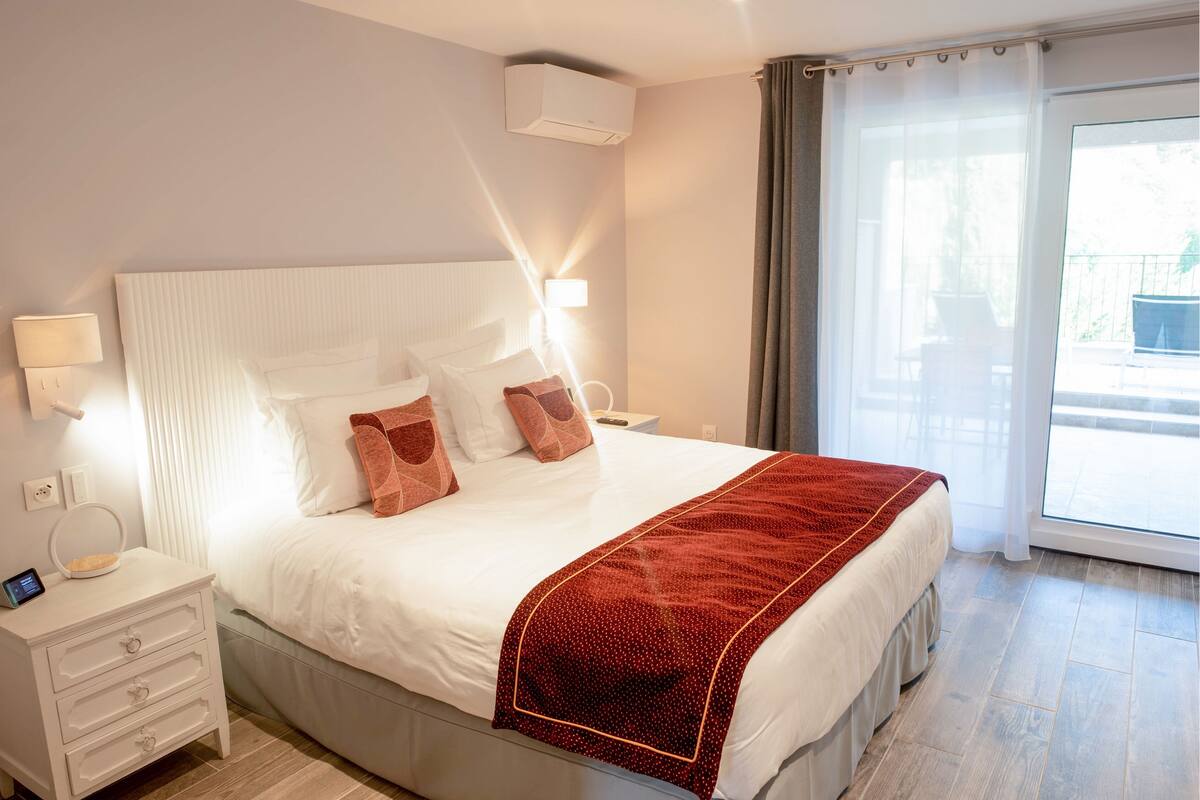 Une chambre d’hôtel avec un lit, une table de chevet, une lampe et une vue par la fenêtre.