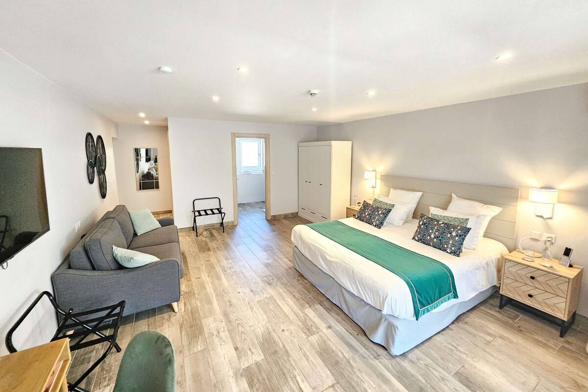 Une chambre spacieuse avec un grand lit, un canapé, un bureau et une armoire.