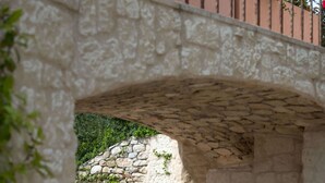A stone bridge leading to a courtyard with a white chair and a stone wall. - Domaine Ribiera, Hotel 5 Etoiles, SPA & Golf - Forcalquier (Niozelles)