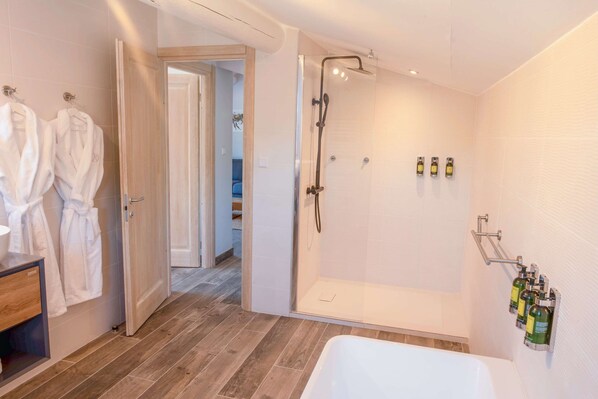 A modern bathroom with a shower, a bathtub, and a wooden vanity.