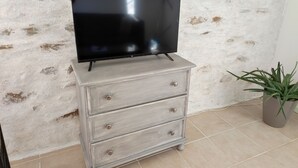 A television on a dresser against a textured wall.