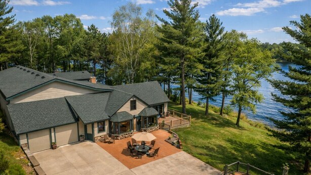 A large house with a covered patio, a deck, and a view of a lake.