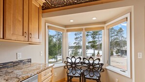 A kitchen with wooden cabinets, a granite countertop, and a dining area with two chairs.