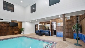 An indoor swimming pool with a seating area and a television.