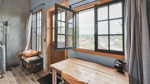 A room with a wooden table, a bench, and a window with a view of houses. - Zen2- Adorable Tiny Home in Davis! Pet Friendly! A/C (Davis)