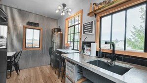 A modern kitchen with a large window, wooden accents, and a rustic design. - Zen2- Adorable Tiny Home in Davis! Pet Friendly! A/C (Davis)