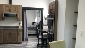 Un espacio habitable compacto con kitchenette, comedor y cama.