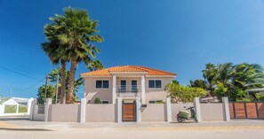 A two-story house with a tiled roof, a gated entrance, and a parked scooter.